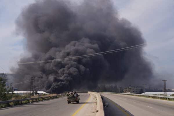 Photo: The smoke rises while the members of the Syrian forces travel in a vehicle in Latakia